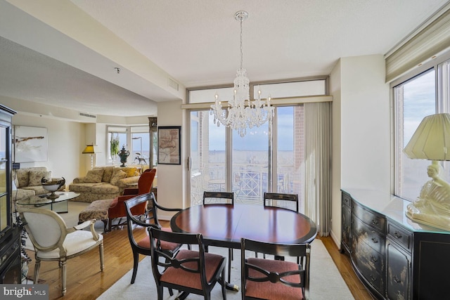 dining room with a notable chandelier, wood finished floors, visible vents, and a healthy amount of sunlight