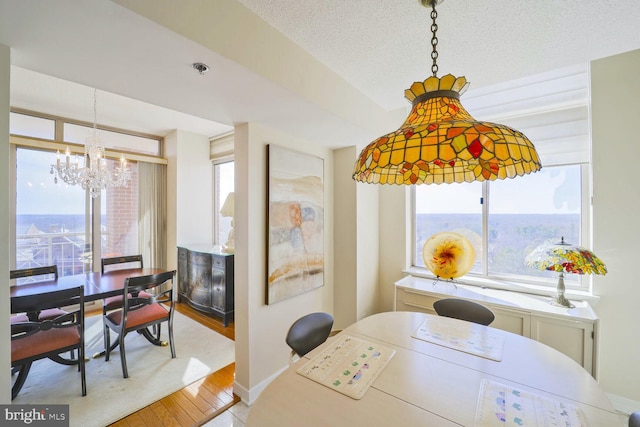 dining area featuring an inviting chandelier, plenty of natural light, wood finished floors, and a textured ceiling