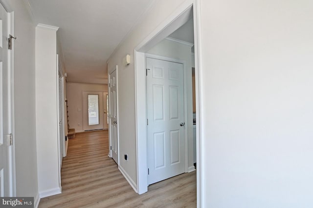 hall featuring crown molding, light wood-style floors, and baseboards