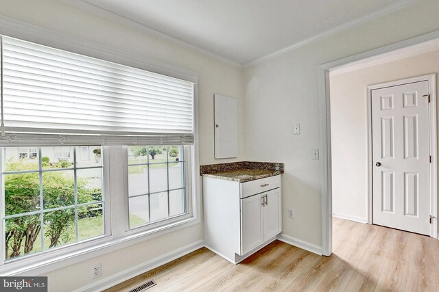 kitchen featuring baseboards, a healthy amount of sunlight, light wood-style flooring, and ornamental molding