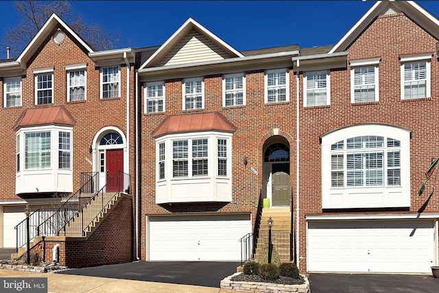 view of property with an attached garage, brick siding, and driveway