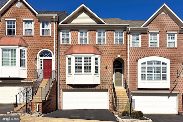 multi unit property featuring brick siding, driveway, and a garage