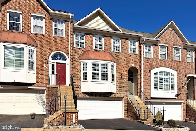 townhome / multi-family property featuring aphalt driveway, an attached garage, and brick siding