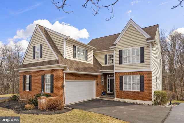 traditional-style home featuring aphalt driveway, brick siding, and a shingled roof