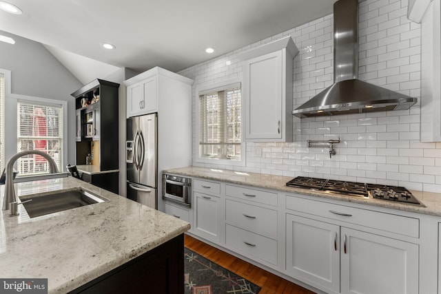 kitchen with a sink, a wealth of natural light, stainless steel appliances, wall chimney exhaust hood, and dark wood-style flooring