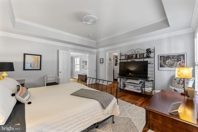 bedroom featuring a raised ceiling, crown molding, and wood finished floors