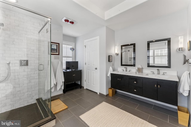 full bathroom with baseboards, double vanity, a sink, a shower stall, and tile patterned floors