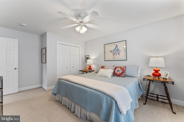 bedroom with ceiling fan, light colored carpet, a closet, and baseboards