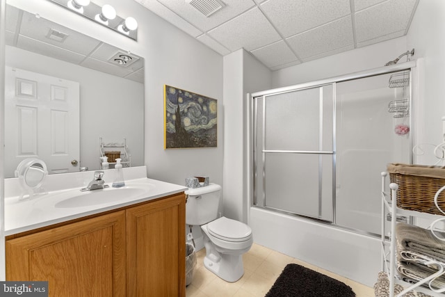 full bathroom featuring visible vents, toilet, a drop ceiling, bath / shower combo with glass door, and vanity