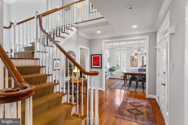 entryway featuring hardwood / wood-style floors, baseboards, recessed lighting, ornamental molding, and a chandelier