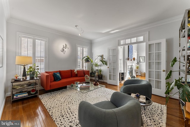 living area featuring a fireplace, wood-type flooring, baseboards, and ornamental molding