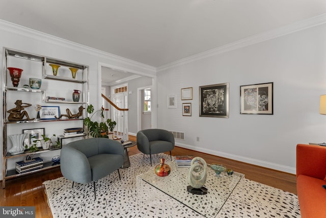 living area featuring wood finished floors, baseboards, visible vents, ornamental molding, and stairs