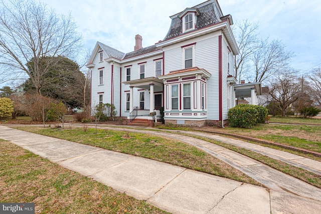 victorian home with mansard roof and a front yard