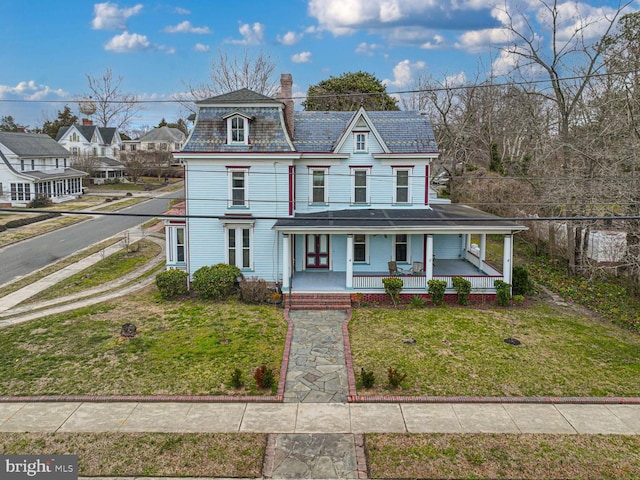 view of front of home with mansard roof, a high end roof, a porch, a front yard, and a chimney