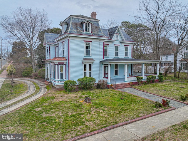 victorian home with a front yard, a porch, a high end roof, mansard roof, and a chimney