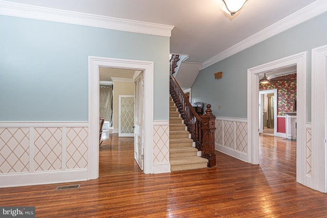 interior space with visible vents, wood finished floors, wainscoting, crown molding, and stairs