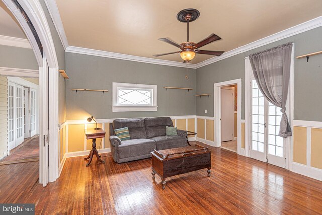 living room featuring ceiling fan, arched walkways, wood-type flooring, and ornamental molding