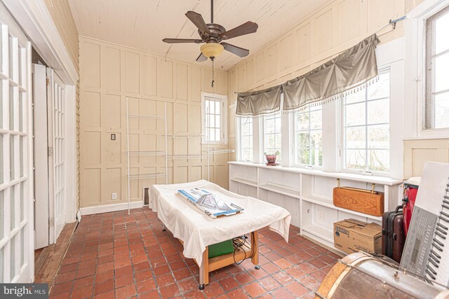 bedroom featuring multiple windows, ceiling fan, pool table, and a decorative wall