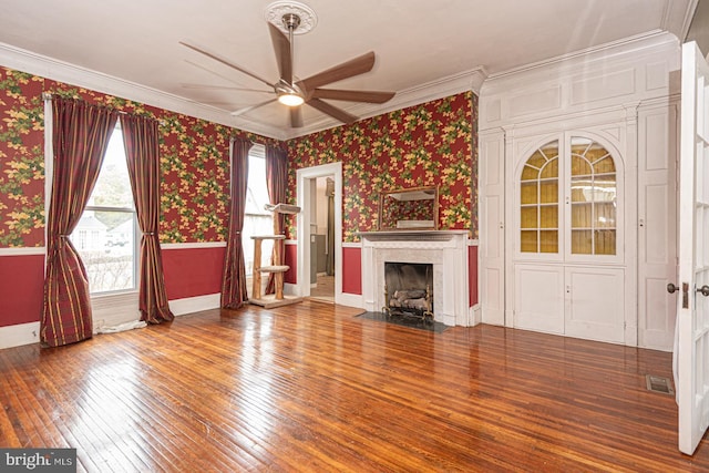 unfurnished living room featuring visible vents, wallpapered walls, a high end fireplace, ceiling fan, and wood-type flooring