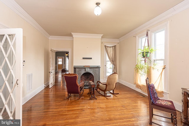 sitting room featuring visible vents, wood finished floors, a fireplace, and crown molding