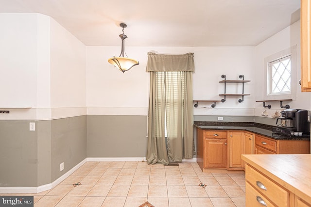 kitchen featuring hanging light fixtures, dark stone counters, light tile patterned flooring, and open shelves