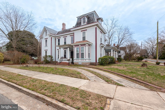 victorian home featuring a front lawn and mansard roof