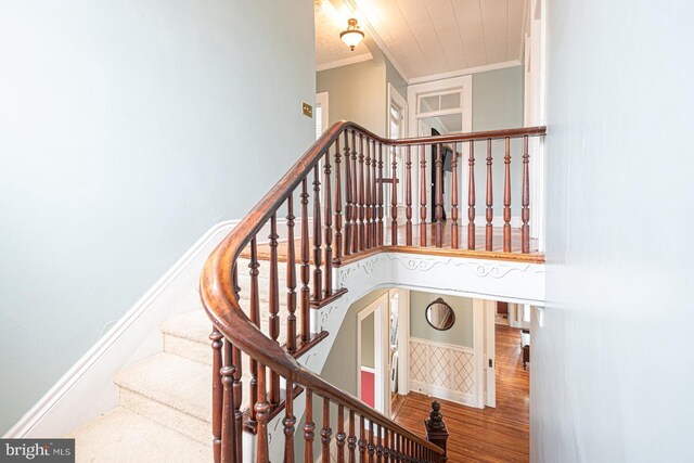 stairs featuring baseboards, wood finished floors, and crown molding