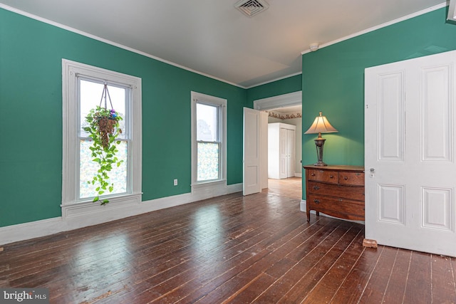 empty room with crown molding, baseboards, visible vents, and dark wood-style flooring