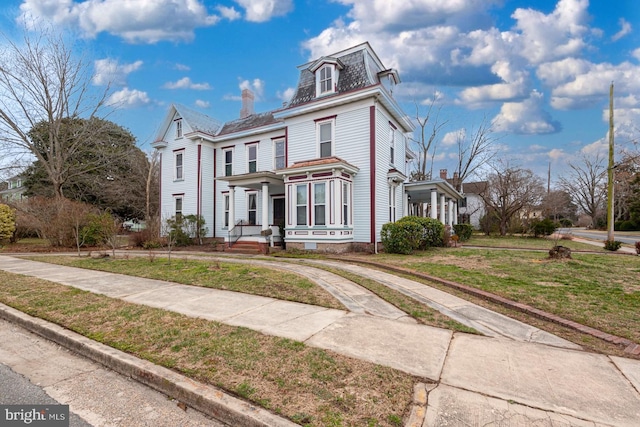 second empire-style home featuring mansard roof and a front yard