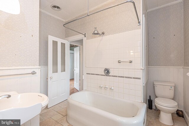 full bath featuring a wainscoted wall, visible vents, crown molding, and wallpapered walls