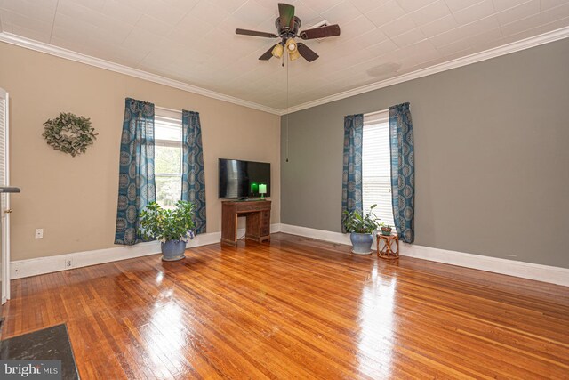 unfurnished living room featuring a healthy amount of sunlight, crown molding, and hardwood / wood-style flooring