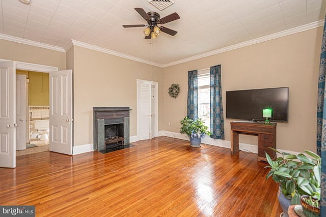 unfurnished living room with wood finished floors, visible vents, baseboards, a fireplace with flush hearth, and crown molding