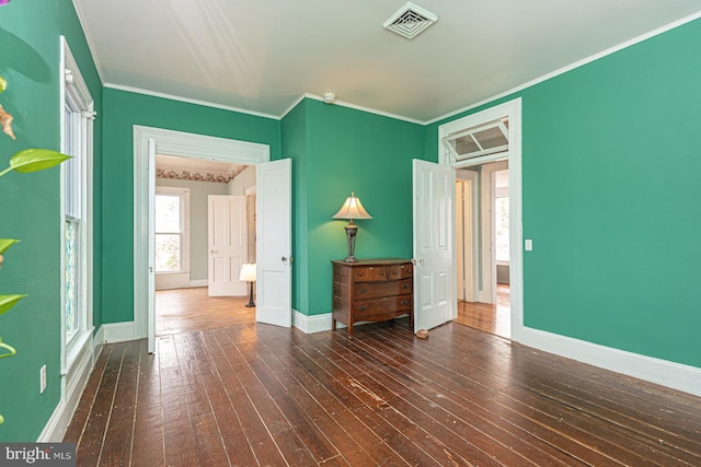 unfurnished room with visible vents, baseboards, ornamental molding, and dark wood-style flooring