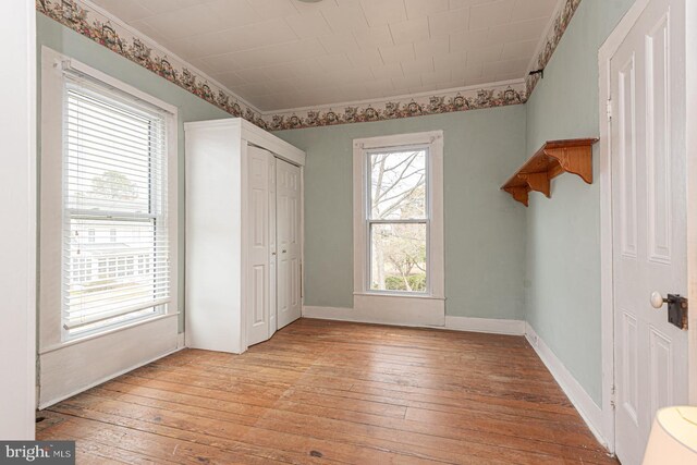 unfurnished bedroom featuring light wood-style flooring, baseboards, and ornamental molding