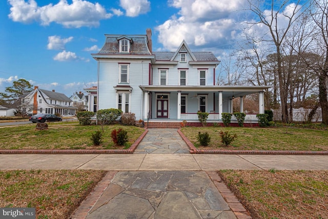 second empire-style home with a front yard, mansard roof, and covered porch