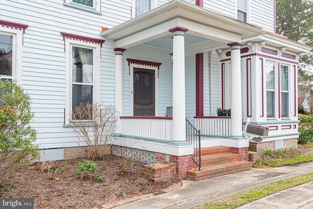 view of exterior entry with a porch and crawl space