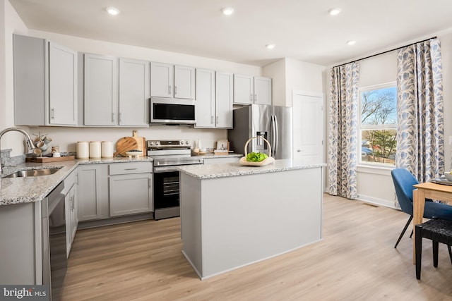 kitchen with light wood-style flooring, gray cabinetry, stainless steel appliances, and a sink