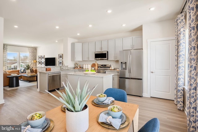 kitchen featuring recessed lighting, stainless steel appliances, light wood-style floors, and a center island