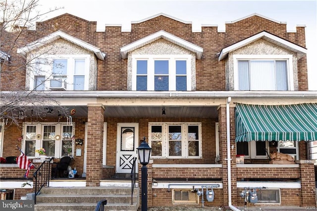 townhome / multi-family property with a porch and brick siding