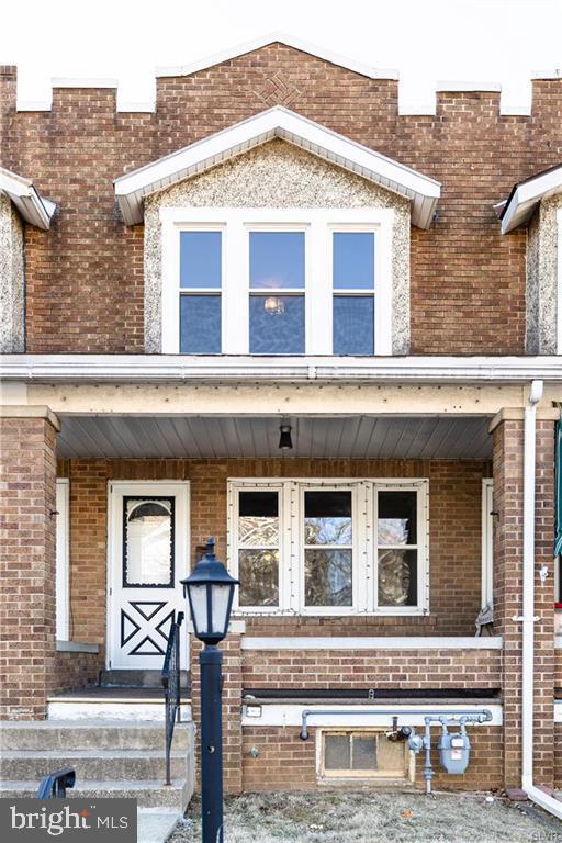 entrance to property featuring brick siding and a porch