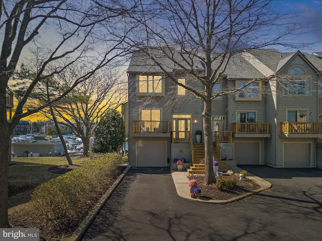 multi unit property featuring aphalt driveway, a garage, and stairs