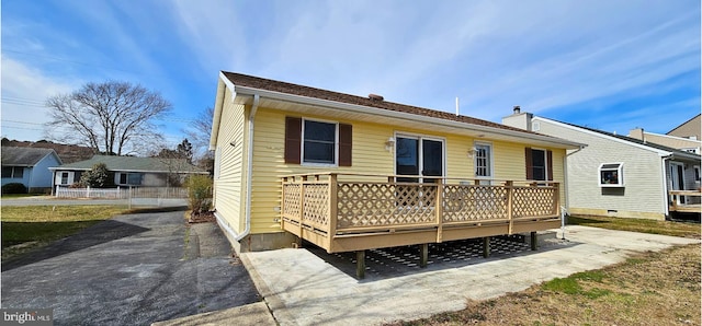 back of house with a chimney, driveway, and a wooden deck