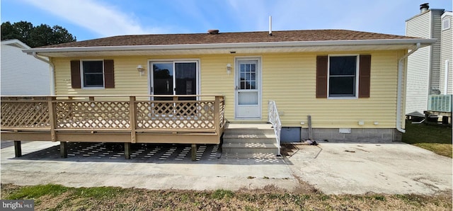 back of property with a wooden deck, a patio, and a shingled roof