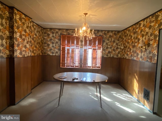 unfurnished dining area featuring wallpapered walls, wooden walls, a wainscoted wall, and a chandelier