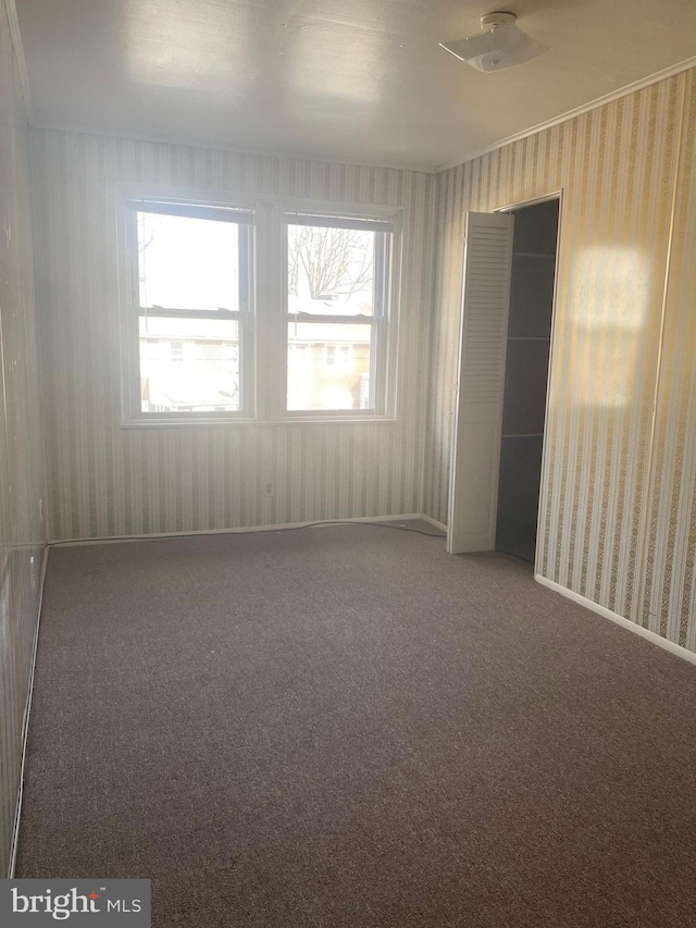 carpeted spare room with wallpapered walls and baseboards