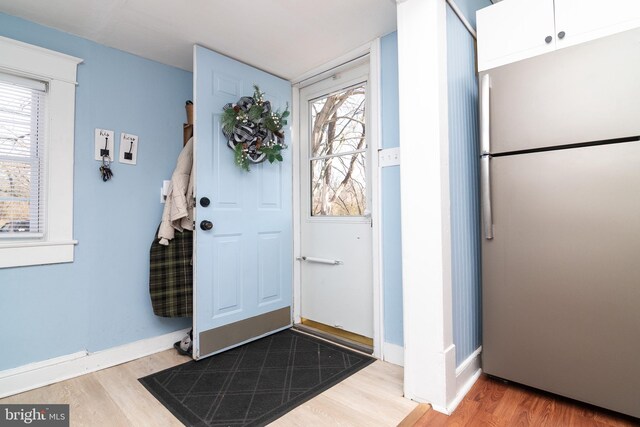 foyer entrance with light wood finished floors, baseboards, and a wealth of natural light