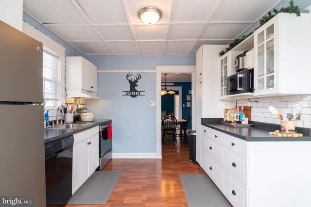 kitchen featuring a sink, stainless steel appliances, dark wood-type flooring, white cabinetry, and dark countertops