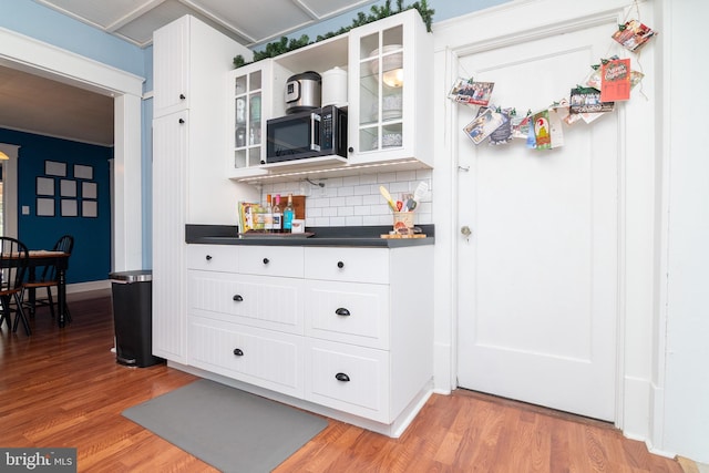 interior space featuring dark countertops, stainless steel microwave, light wood finished floors, and white cabinetry