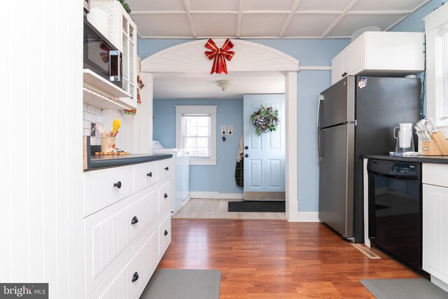 kitchen with dark countertops, dishwasher, white cabinetry, and wood finished floors