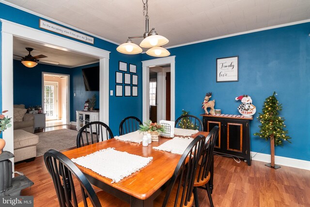 dining space with a ceiling fan, wood finished floors, baseboards, and ornamental molding